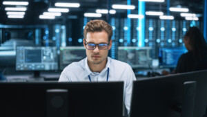 Focused System Administrator or Consultant Look at the Screen and Saves Backup Data in Dark Evening Room Workplace Station Indoors. Network Technologies Concept